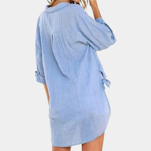 Light blue linen tunic dress for women, featuring a knee-length design and a loose fit. The dress has short sleeves, a round neckline, and a slightly cinched waist.
