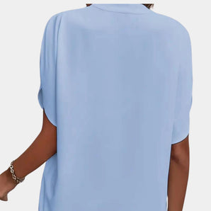 Light blue short sleeve blouse with elegant back button closure, featuring a classic round neckline and a relaxed fit perfect for casual or dressy occasions.