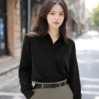 A woman wearing a light blue blouse with a minimalist design, featuring long sleeves and a casual fit suitable for office wear.