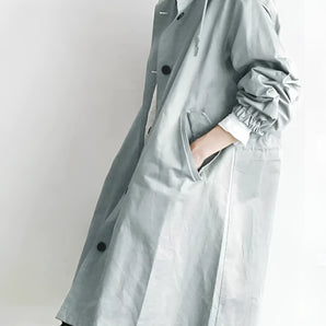 Light gray women's oversized double-breasted trench coat with long sleeves, wide lapels, and a belted waist.