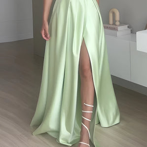 Long light green satin maxi skirt with a high waist and elegant split-front design, showcased in a formal setting.
