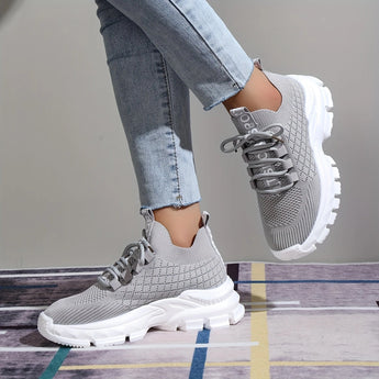 Light grey women's fashion sneakers featuring breathable mesh and a cushioned sole, displayed against a neutral background.