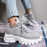 Light grey women's fashion sneakers made of breathable mesh with a cushioned sole.