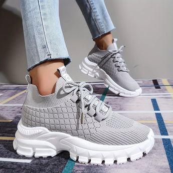 Light grey women's fashion sneakers made of breathable mesh with a cushioned sole.