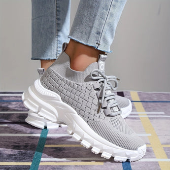 Light grey women's fashion sneakers made of breathable mesh with a cushioned sole, displayed on a model's foot.