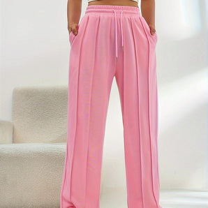 Women's light pink high-waist joggers featuring a stylish and comfortable design, highlighting elements like the waistband and knee area, with a focus on a soft, peachy pink color.