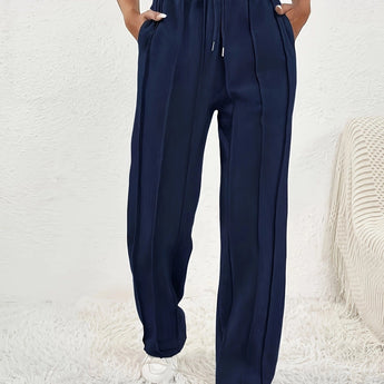 A woman wearing light pink high-waist joggers paired with a casual t-shirt, showcasing stylish sweatpants suitable for a relaxed, sporty look.