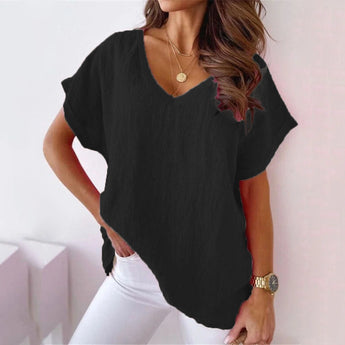 Woman wearing a light pink V-neck blouse with short sleeves and a relaxed fit, suitable for casual summer outings.