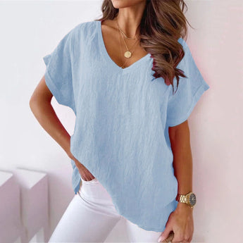 Woman wearing a light pink V-neck blouse with short sleeves, standing with her hands on her hips.