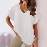 Woman wearing a light pink v-neck blouse with short sleeves, posing with her hand on her waist, showcasing the breathable and stylish summer top.