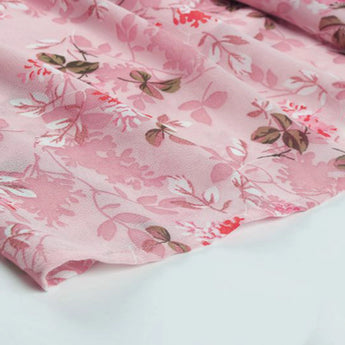 Light pink V-neck blouse with a delicate floral print, featuring short sleeves and a soft pattern in shades of magenta and peach.