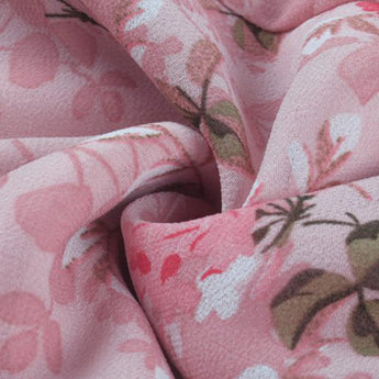 Light pink floral blouse with a V-neck design, featuring a delicate flower print and long sleeves.