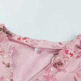 Light pink v-neck blouse featuring a delicate floral print, with long sleeves and a stylish silk finish.