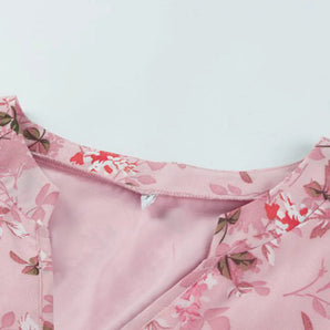 Light pink v-neck blouse featuring a delicate floral print, with long sleeves and a stylish silk finish.