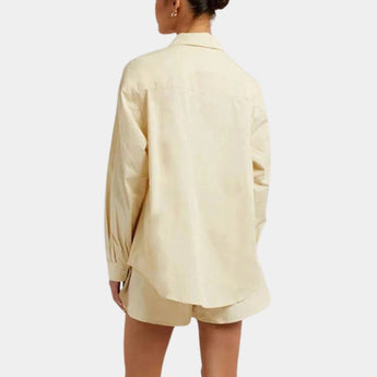 A light yellow women's oversized silk shirt with a luxurious soft touch, featuring long sleeves and a classic collar, photographed on a model.