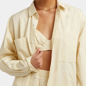 Light yellow women's oversized silk shirt with a luxurious soft touch, featuring long sleeves, a classic collar, and button detailing, styled as formal outerwear.