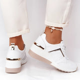 Lightweight beige women's low-top fashion sneakers displayed on a person's feet, showcasing their chic and breathable design.