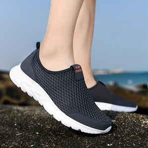 Lightweight breathable slip-on women's sneakers with a water-resistant design in a grey color, suitable for walking and casual sportswear activities.