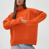 Orange chunky knit turtleneck sweater with long sleeves, suitable for cozy winter fashion, displayed on a person wearing jeans.