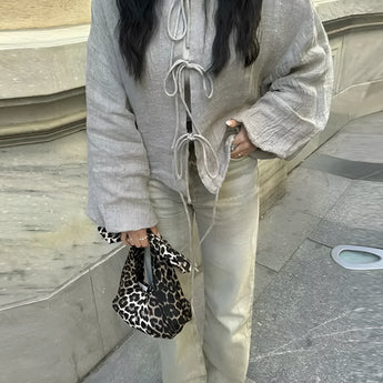 Linen blouse with a collar and long sleeves paired with cream pants, styled with eyewear, embodying urban chic street fashion.