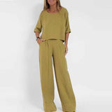 A woman wearing a green linen jumpsuit in a casual wide-leg high waist style, suitable for summer. The outfit features a collar and short sleeves, perfect for a relaxed yet chic look.