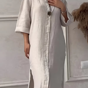 Linen midi dress in a neutral apricot color, featuring a button-down front and three-quarter sleeves, worn by a fashion model, showcasing a relaxed fit with emphasis on the shoulder, neck, and waist areas.