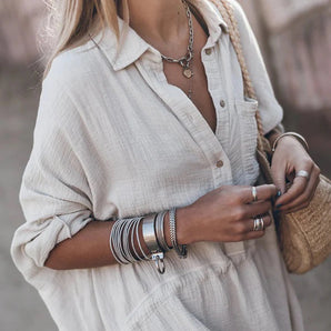 Woman wearing a linen shirt, styled as a casual summer blouse, with lightweight fabric suitable for the beach. The shirt has long sleeves and is paired with sunglasses.