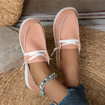 Eco-friendly breathable pink women's sneakers on a wooden surface with a focus on the shoe's design and material, worn by a person with bare legs, highlighting the casual and comfortable style.