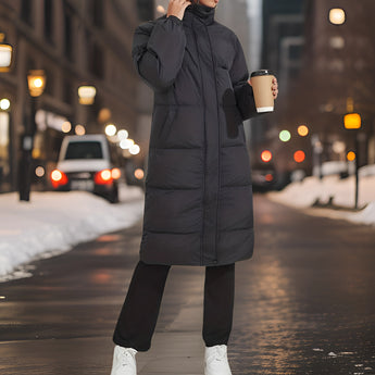 
A stylish women's long black insulated winter down coat in size XL, designed for urban outerwear. The coat features a sleek overcoat style with a high collar, full sleeves, and a fitted waist, suitable for keeping warm in snowy conditions.