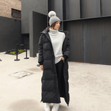 Woman wearing a long black oversized puffer coat, full-length quilted jacket with sleeves, suitable for formal wear and events.
