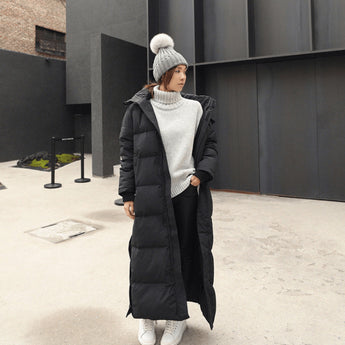 Woman wearing a long black oversized puffer coat, full-length quilted jacket with sleeves, suitable for formal wear and events.