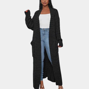 
A woman wearing a long black ribbed oversized knit cardigan, suitable for winter wear, featuring a collar and long sleeves, paired with a bag over her shoulder.