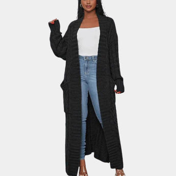 
A woman wearing a long black ribbed oversized knit cardigan, suitable for winter wear, featuring a collar and long sleeves, paired with a bag over her shoulder.