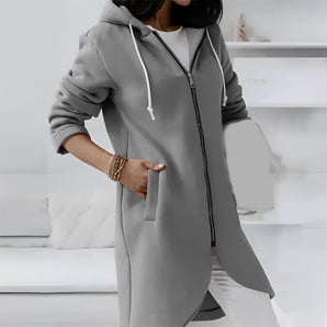 
A model wearing a long grey women's zip-up hoodie dress in size 5XL. The dress is stylish and lightweight, featuring long sleeves, a collar, and a waistline that accentuates the figure. The model is shown from the waist up, with one arm slightly bent at the elbow, and wearing sunglasses.
