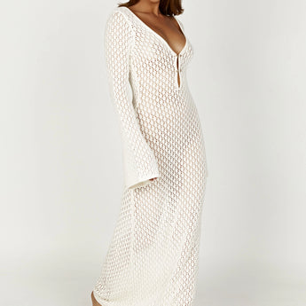 Long sleeve white crochet midi dress worn as a bohemian beach cover-up, featuring intricate crochet patterns, a relaxed fit, and knee-length design.