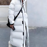 Long beige oversized hooded puffer coat with sleeves extending to wrists, knee-length design, featuring a collar and thermal insulation, suitable for winter.