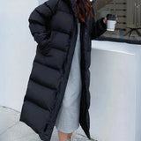 Long white hooded puffer coat in an oversized fit, featuring black and grey accents, with long sleeves and a waist-length design. The coat includes a collar and resembles a trench coat style, suitable for thermal winter wear.