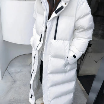 Long white oversized hooded puffer coat with thermal insulation, featuring a sleek design and button details, perfect for winter fashion.