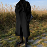 A stylish long white men's double-breasted winter coat worn outdoors, showcasing urban fashion with a formal design.