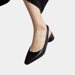 Black leather women's low-heel flats focusing on minimalist design, shown on a model's feet. The shoes are designed for comfort and are suitable for fashion events or everyday wear.