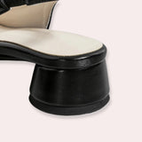 Women's minimalist black leather low-heel flats placed on a textured surface, highlighting their sleek design and comfort-focused construction.
