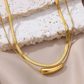Luxurious double layer gold necklace on beige background featuring a minimalist and versatile choker design.
