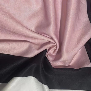 Luxurious pink satin fabric draped elegantly, showcasing its smooth texture and high-quality sheen with a focus on its rich magenta tint, suitable for fashion and sewing projects.