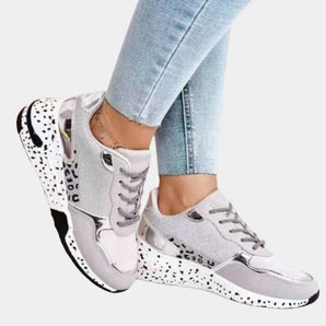 Luxurious women's designer sneakers with an animal print and metallic accents, showcased in a stylish fashion setting featuring denim and sportswear elements.