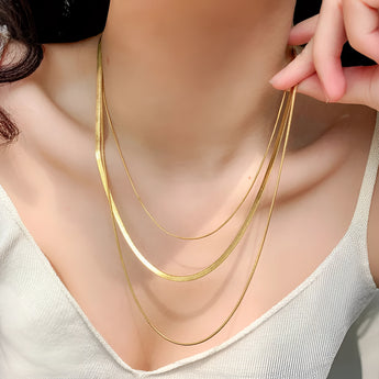 A close-up of a person wearing a luxury 18K gold plated snake chain necklace, showcasing its sleek and elegant design on their neck.