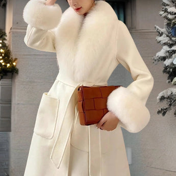Luxury beige winter coat with faux fur collar, designed as a wool overcoat. Features include long sleeves, a stylish waistline, and a sophisticated trench coat style. Model is accessorized with a matching bag and gloves.