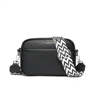 Luxury black leather crossbody bag featuring a geometric patterned strap in shades of magenta, with a sleek rectangular shape, designed for a stylish and fashionable look.