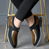 Luxury black leather men's formal shoes with a designer checkered pattern, worn by a person dressed in formal attire.