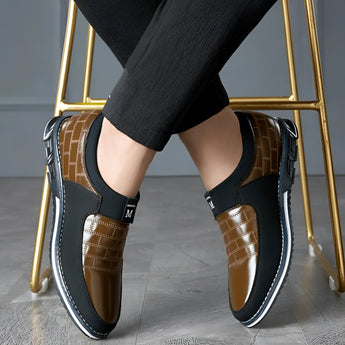 Luxury black leather men's formal shoes with a designer checkered pattern, worn by a person dressed in formal attire.