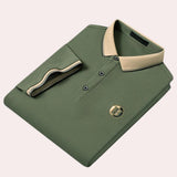 Luxury black polo shirt with contrast green collar, featuring logo embroidery and buttons, shown in 2XL size.